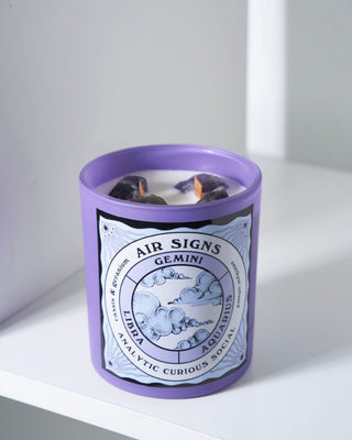 North Muse 'Air Signs' candle in a purple jar featuring zodiac signs Gemini, Libra, Aquarius with embedded crystals.