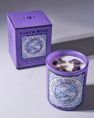 North Muse 'Air Signs' candle in a purple jar with matching box, featuring zodiac signs Gemini, Libra, Aquarius and embedded crystals.